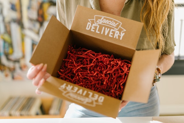 A girl holds a cardboard box with filler for delivery